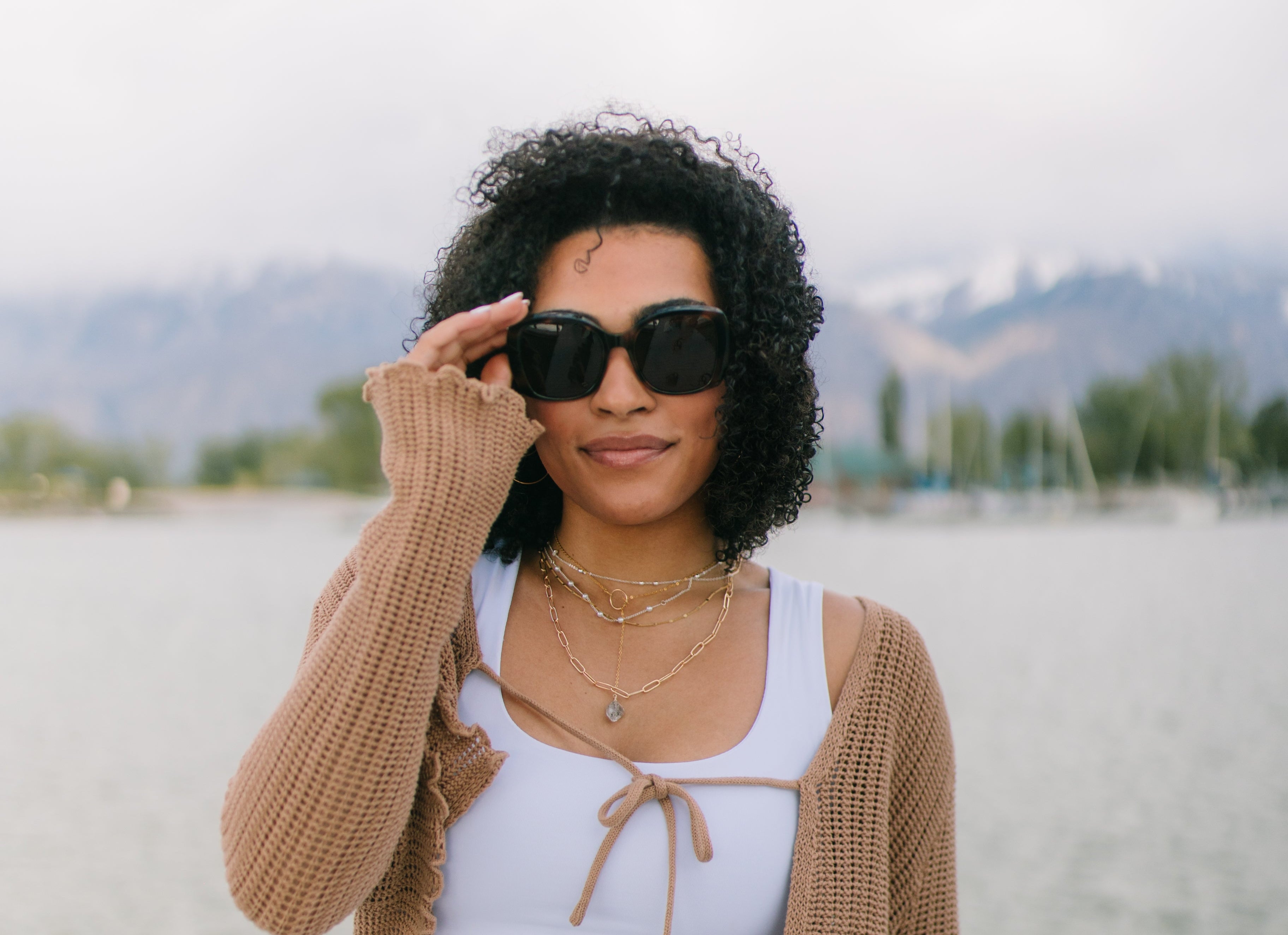 Woman wearing sunglasses and a beige cardigan on a beach