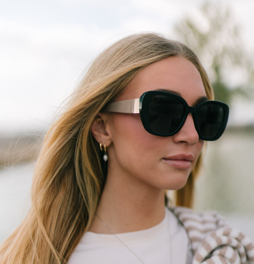 Woman wearing black sunglasses with a blurred outdoor background