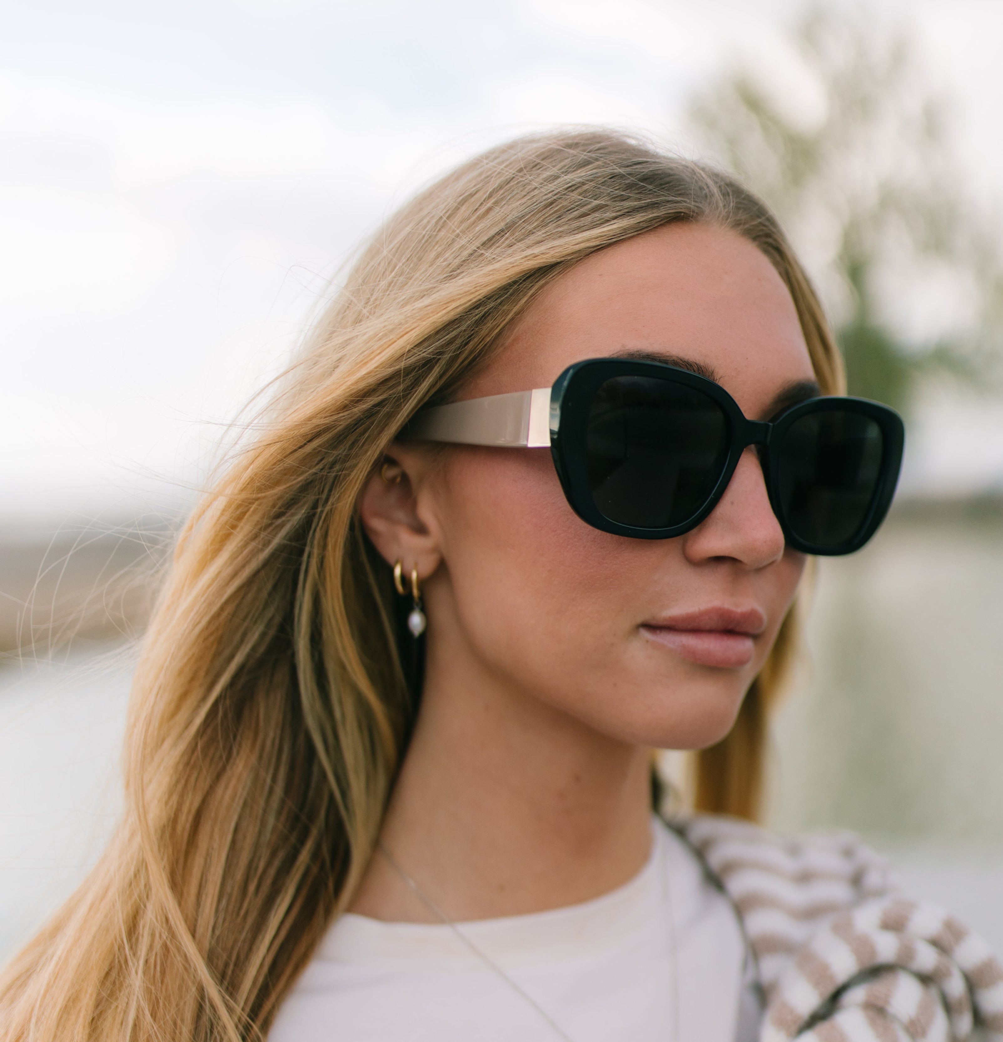 Woman wearing black sunglasses with a blurred outdoor background