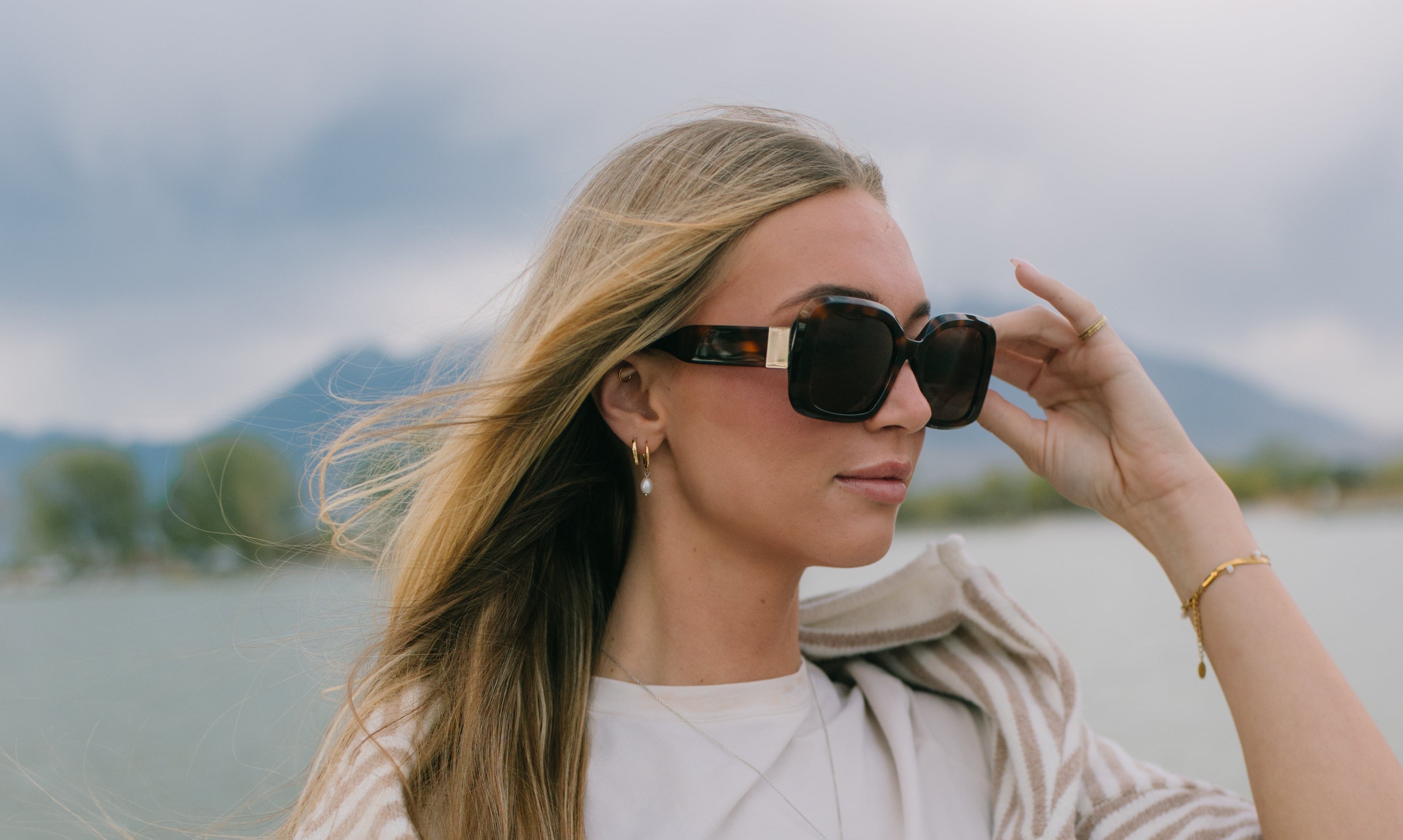 woman with brown tortoise sunglasses on near the water.