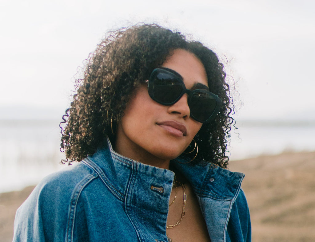 Woman wearing sunglasses and a denim jacket outdoors