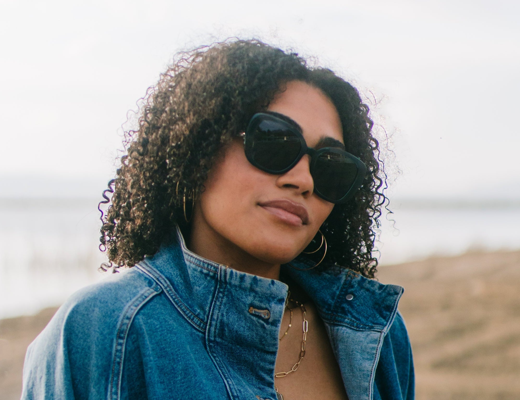 Woman wearing sunglasses and a denim jacket outdoors