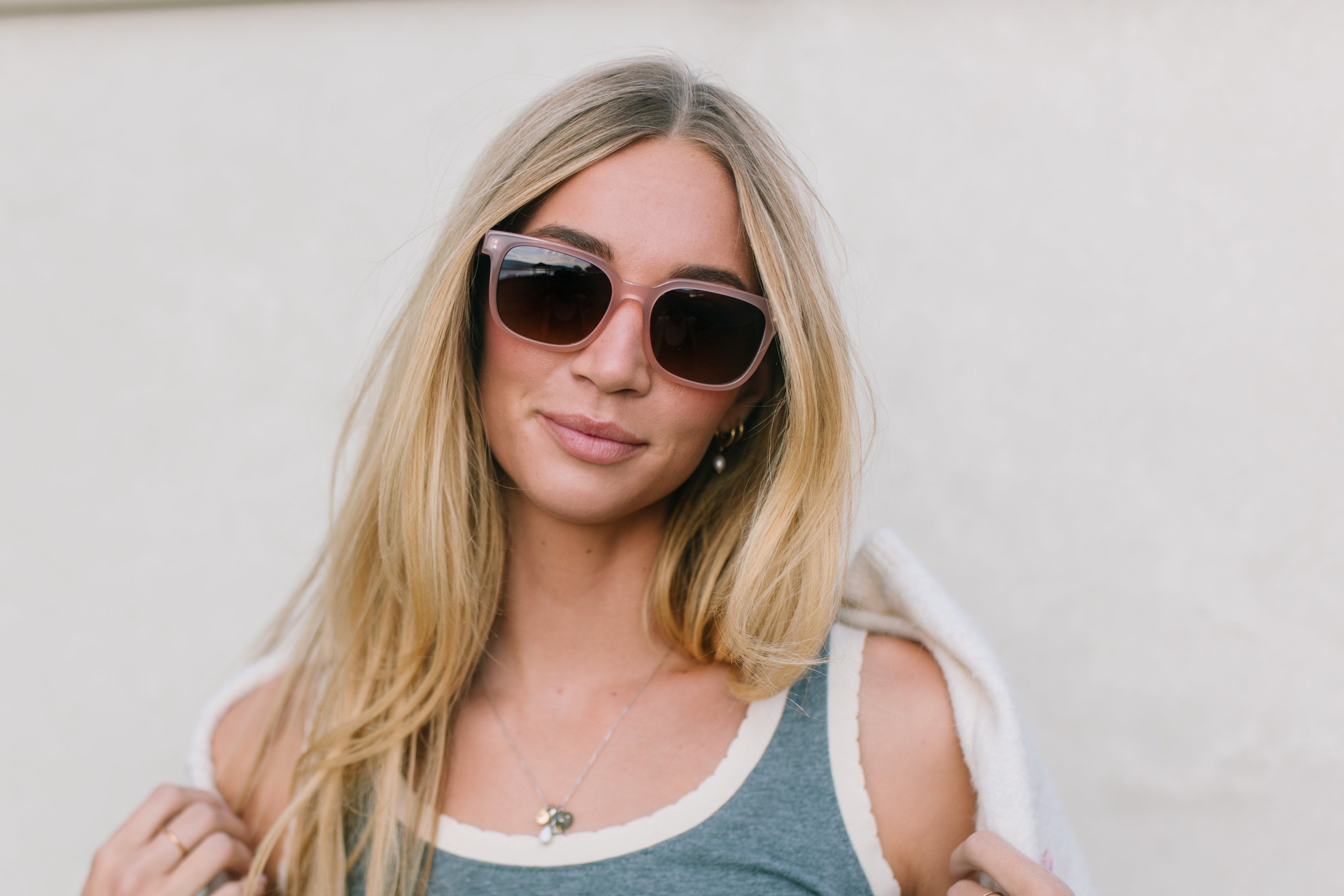 Woman wearing sunglasses and a tank top with a blurred outdoor background
